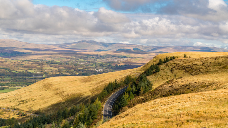 A road creeps up a wild mountain ridge with views over the South Wales valleys