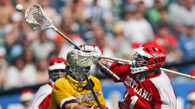 A Cortland lacrosse player competing for the ball during a college match.