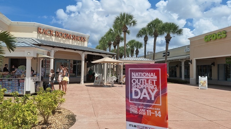 People shop beneath palm trees at Ellenton Premium Outlets