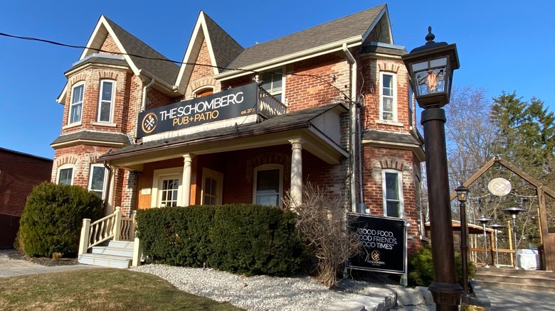 Victorian brick building with the Schomberg Pub + Patio sign and street lamp