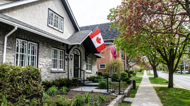 beautiful stone house with Canadian flag on a tree-lined street