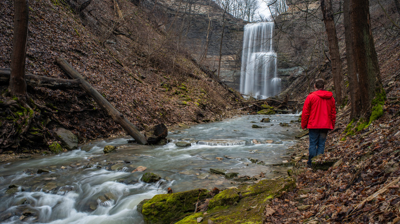 Child in bright red raincoat standing before Felker's Falls waterfall