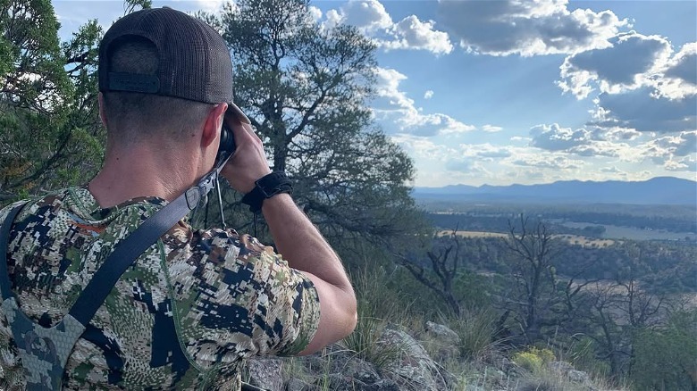 Man holds binoculars overlooking mountains in Reserve, New Mexico