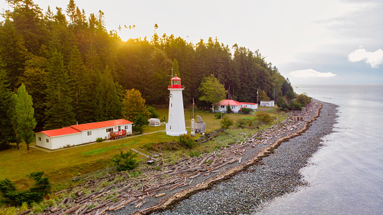 Historic lighthouse on Quadra Island in British Columbia with pebble beach and water in foreground