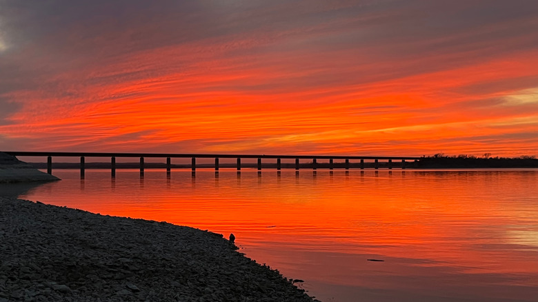 Orange sunset over Lake Whitney with bridge spanning across the horizon.