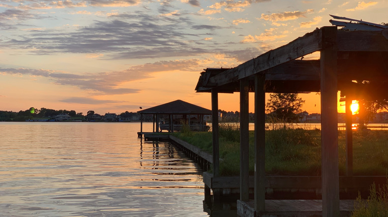 Sunset on Lake Conroe with empty boathouse and green grass