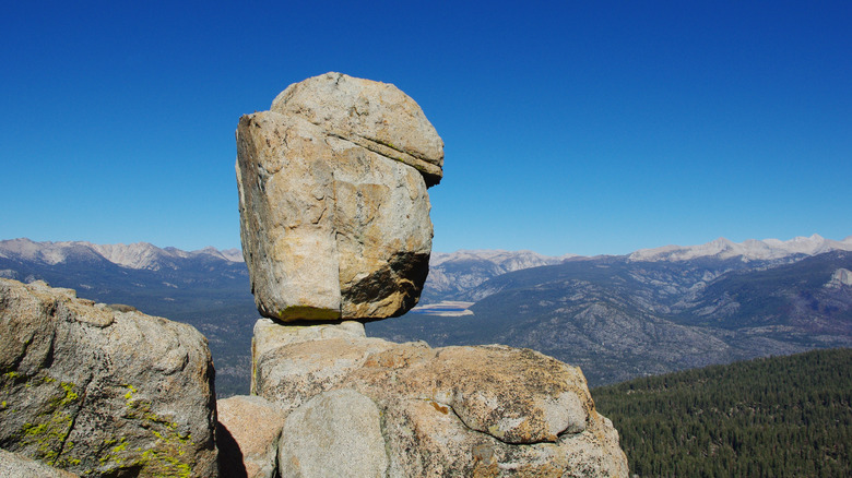 Rocks rise above a trail with views of Lake Edison in the distance