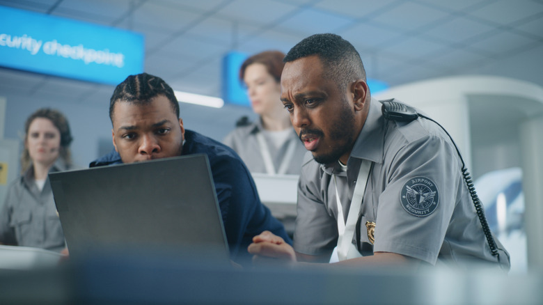 Two men using a laptop in the airport