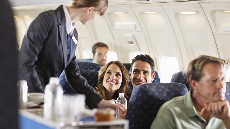 Flight attendant serving someone a water bottle on an airplane