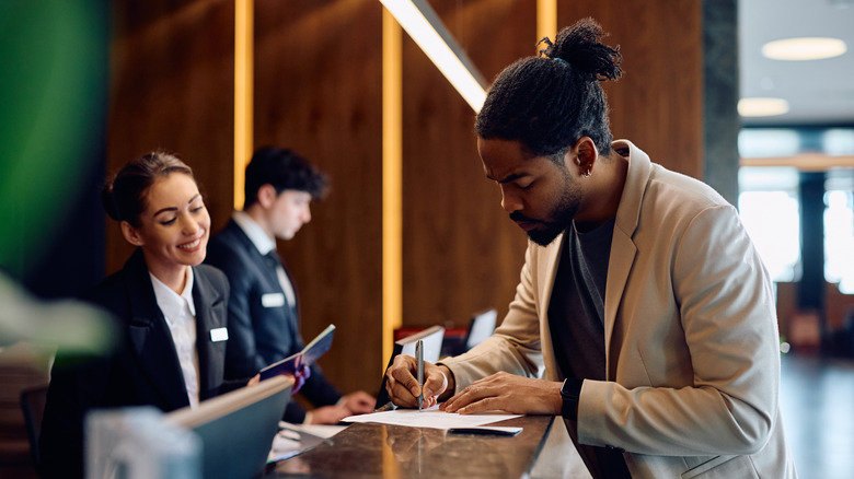 Man filling form at hotel reception