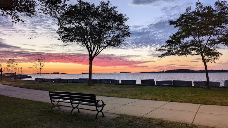 A walking trail lined with benches on Castle Island at sunset in South Boston, Massachusetts
