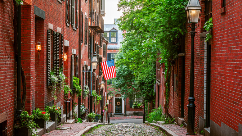 a cobblestoned streed with red brick buildings and gas lamps