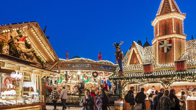 Festive lights on stalls, people shopping, and a carousel in Birmingham
