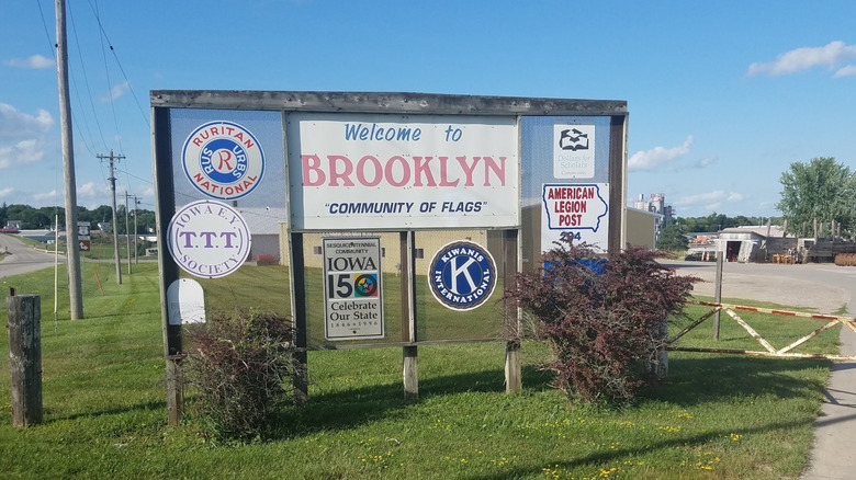 A sign welcoming travelers to Brooklyn, Iowa, with the slogan "Community of Flags"