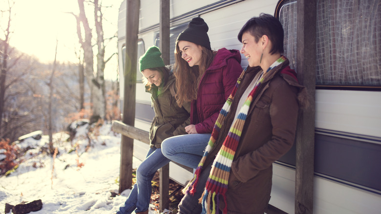 Three friends laughing outside RV