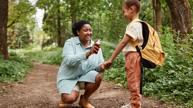 A mother sprays her child with bug spray