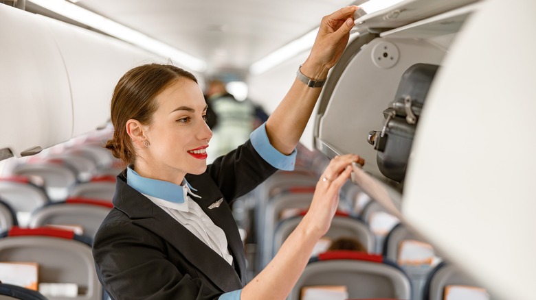 Flight attendant checking overhead bin