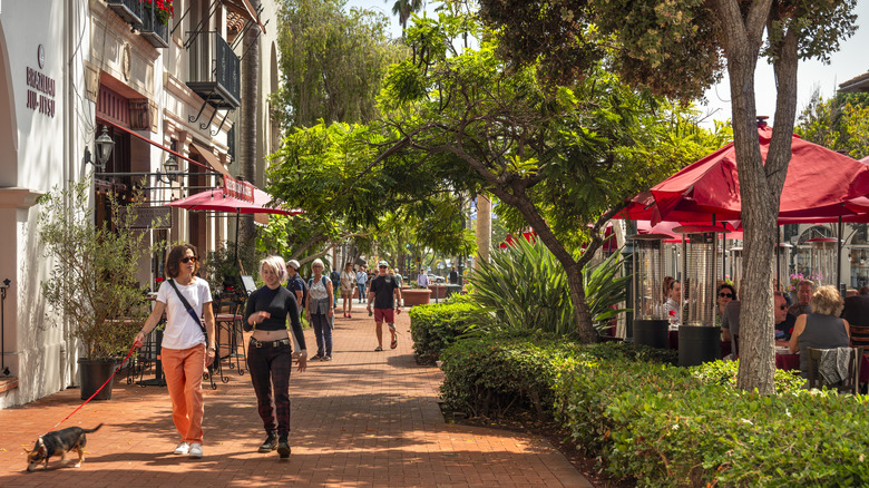 People stroll down a tree-shaded street in Santa Barbara, CA
