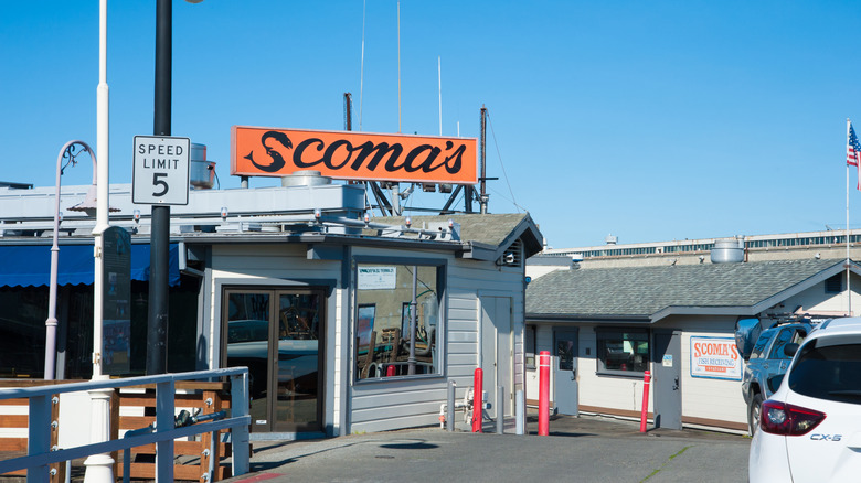 The white facade of Scoma's Restaurant at Fisherman's Wharf San Francisco with the orange "Scoma's" sign.
