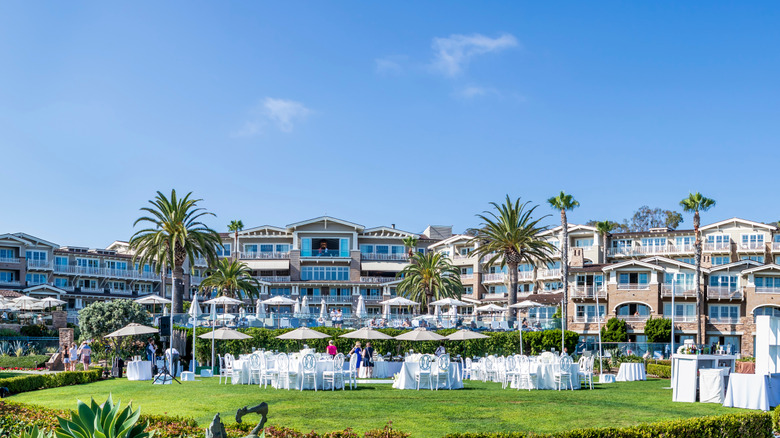 Exterior of Montage Laguna Beach, with palm trees and white tables set up for an event