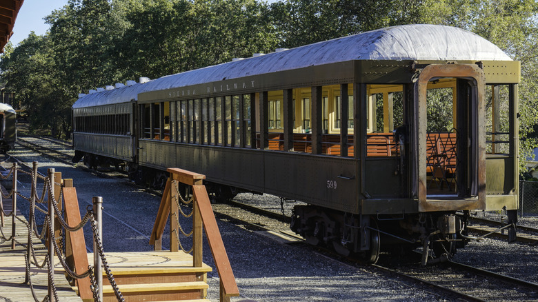 Green vintage 1800s locomotive outside depot