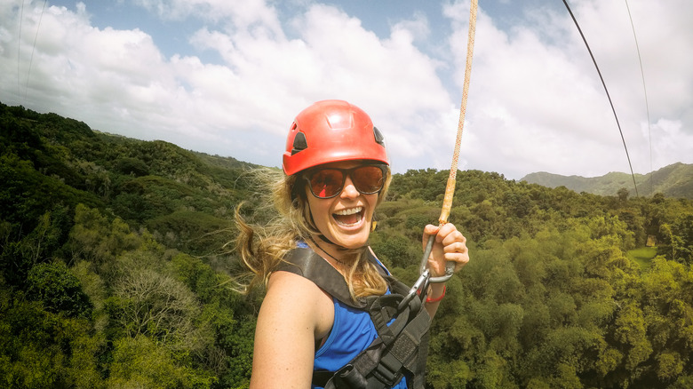 A woman enjoying a ride on a zipline over a tree canopy