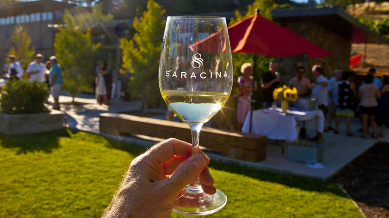 Saracina Vineyards wine glass in front of a party of wine-tasters