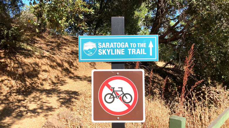 A trail marker on a shaded path reads "Saratoga to the Skyline Trail" at Saratoga Quarry Park.