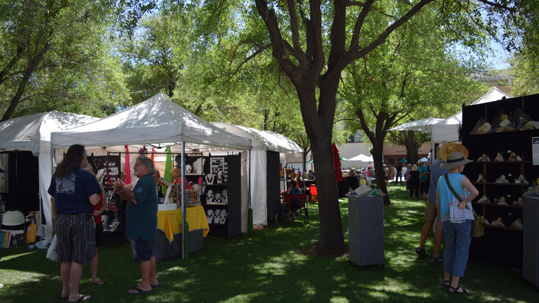 Artists at their booths showcasing artwork under the trees at the Indian Wells Art Festival