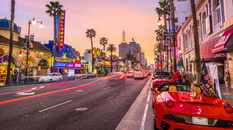Hollywood Blvd at dusk with red cars, palm trees, neon signs