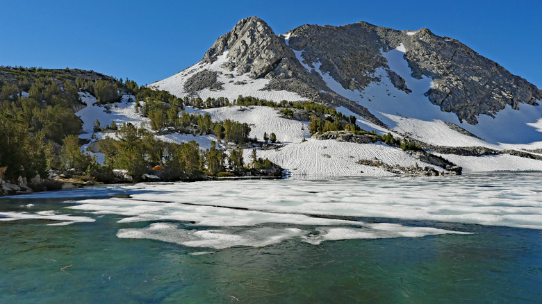 Ice thawing on Ruby Lake in Eastern Sierra, with mountain peaks and forest beyond