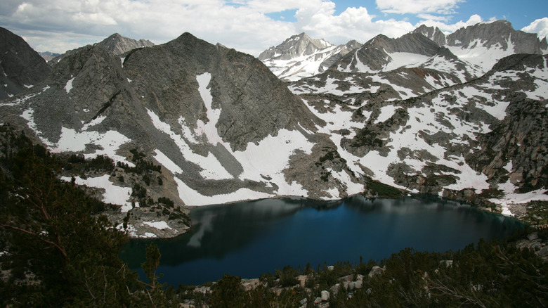 Blue water of Ruby Lake surrounded by snowy granite mountain peaks in California