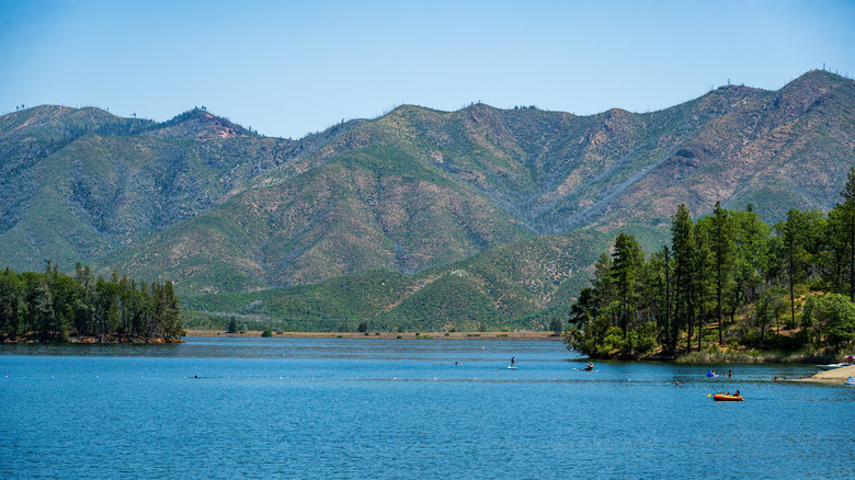 Whiskeytown Lake in Whiskeytown National Recreation Area, California, surrounded by mountains and trees, with people engaging in water recreatin
