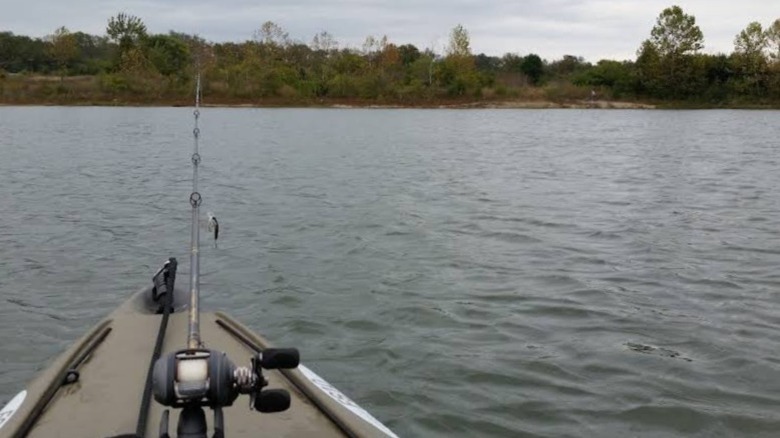 The nose of a kayak in the water with a fishing pole sticking out of the front