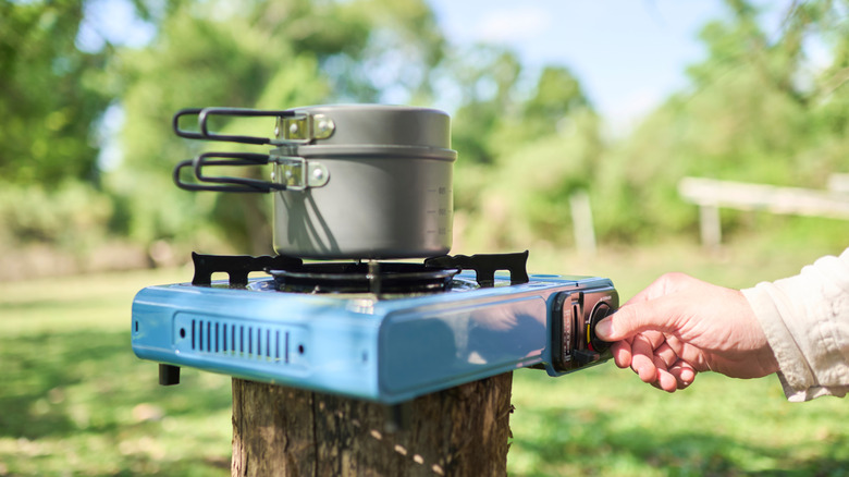 Hand turning on a portable camping stove