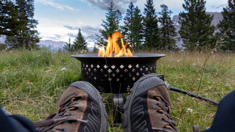 Traveler relaxing by a gas fire pit while camping
