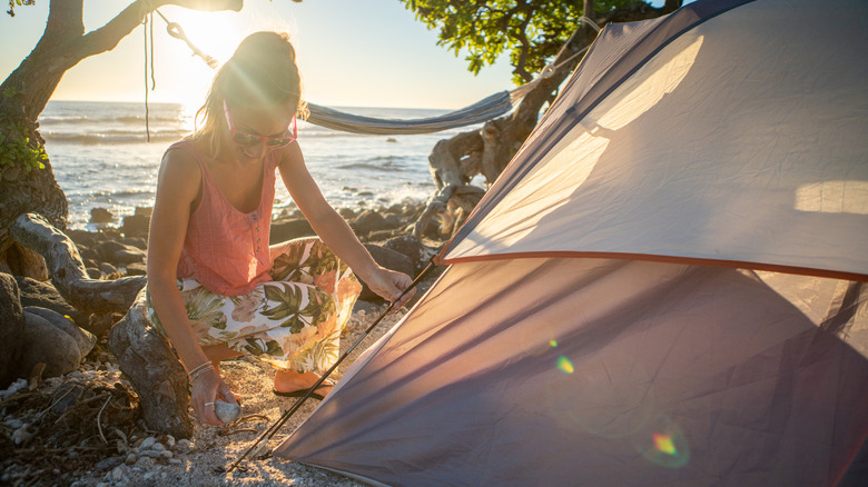 A woman on the beach pitching a tent