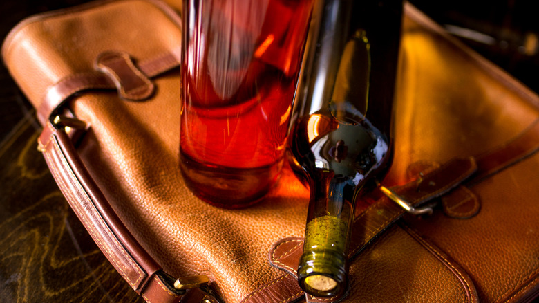 Bottles of wine laying on top of a leather satchel