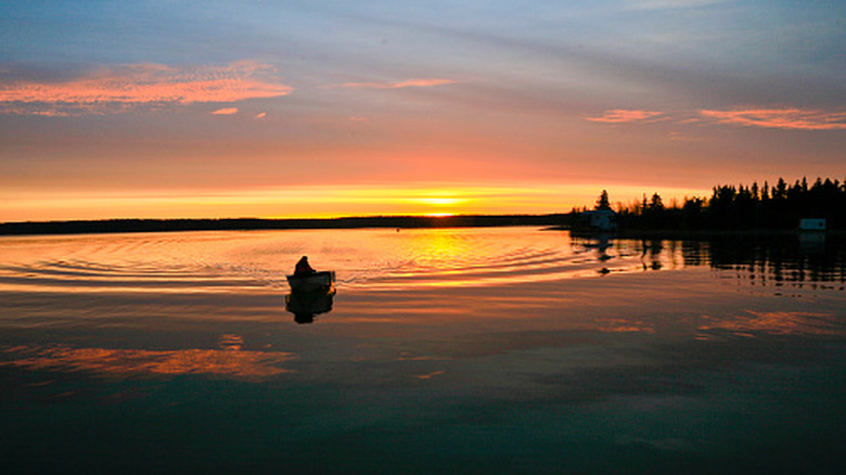 A small outboard boat silhouetted in the sunrise on Yellowknife Bay, Great Slave Lake