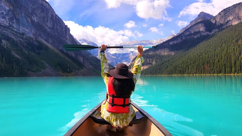 A woman in a canoe on Lake Louise surrounded by mountains in Banff National Park, Canada
