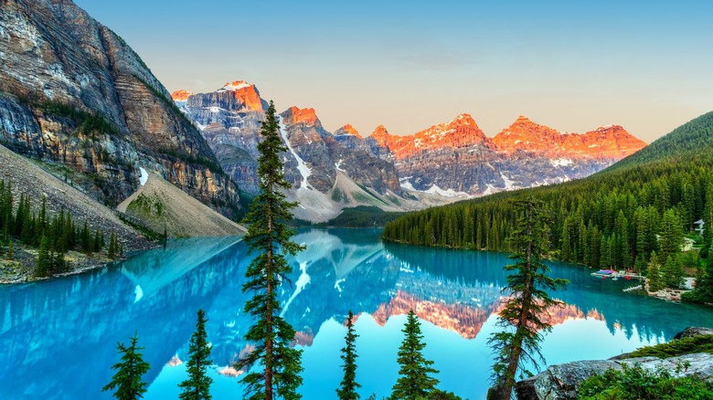 Sunrise over Moraine Lake in Banff National Park, Canada tips the mountains in red-gold and reflects in the blue lake waters