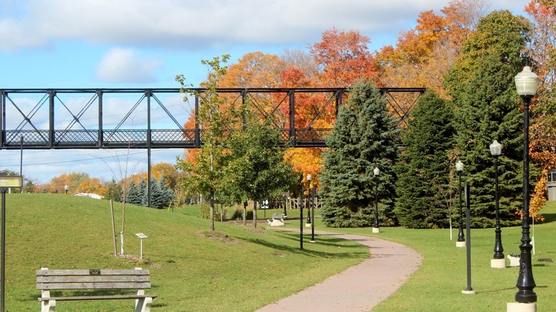 Lions Heritage Park, with a walking trail, lawns, and a black train bridge in Palmerston, Ontario.