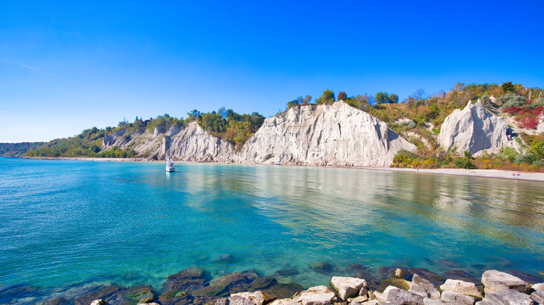 Large cliffside along blue water and trees at Scarborough Bluffs on Lake Ontario, Canada