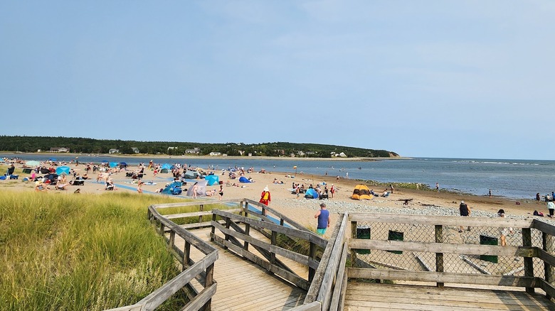 Sandy beach with boardwalk access and calm sea.