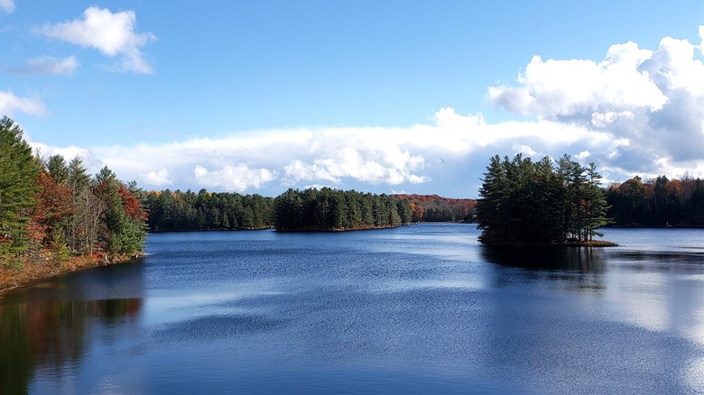 A large lake with an island in the middle lined by fall foliage