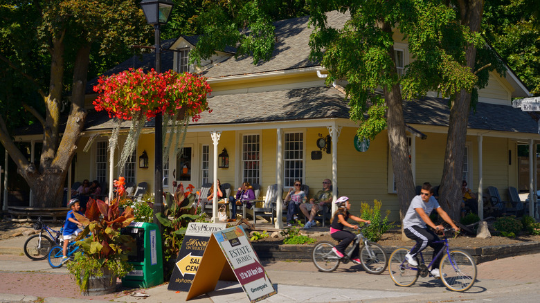 People cycle by a historic yellow house