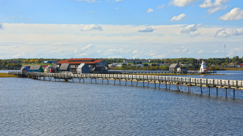 A long boardwalk pier over a steely ocean at Bouctouche Beach in Bouctouche, Canada, with a crisp blue sky comprising of multiple kinds of clouds (distant cirrostratus and lower stratus clouds with nearer cumulus clouds)