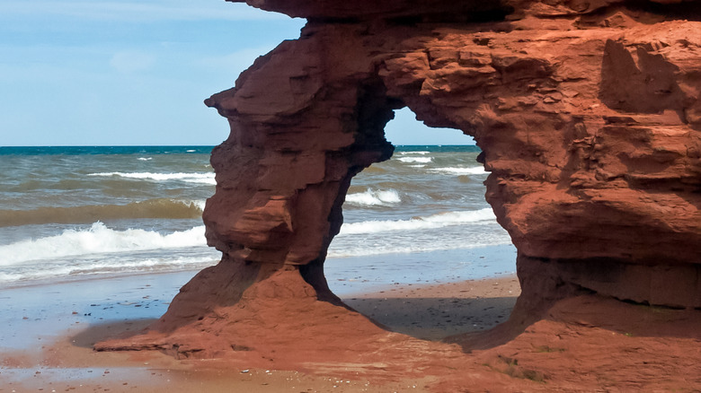 A sandstone rock forming a tunnel on Thunder Cove Beach with waves rolling onto the sand
