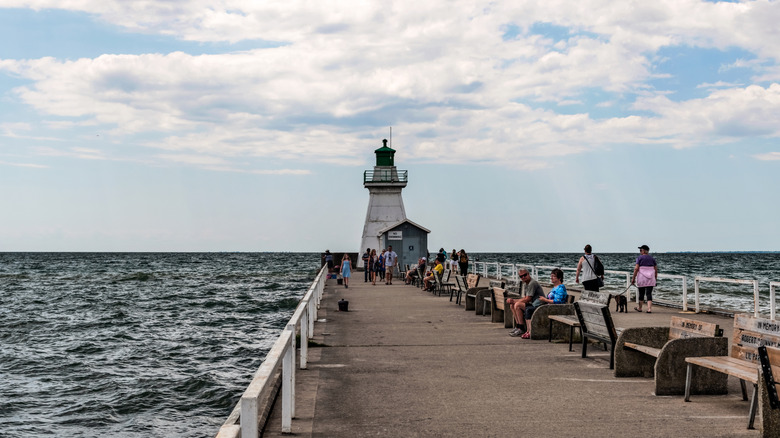 People sitting along the pier in Port Dover, Ontario with historic lighthouse