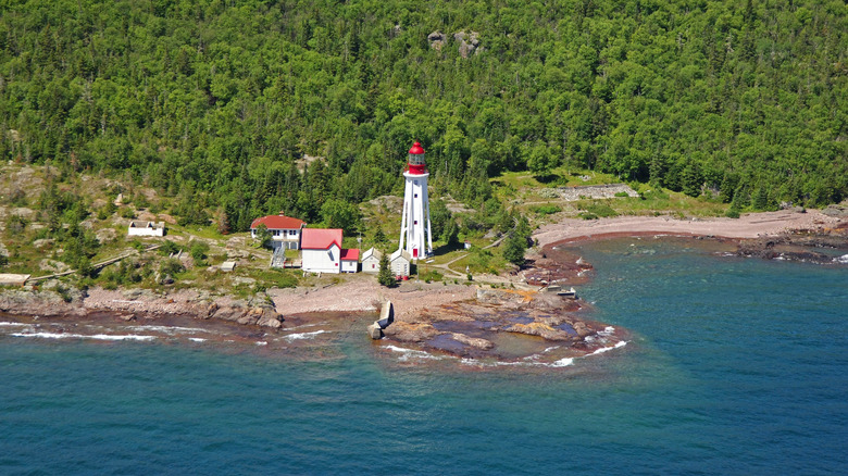 The lighthouse surrounded by forest and blue water on Michipicoten Island